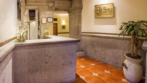 A hallway with a stone bench, a potted plant, and a sign for Hotel Palacio Mayor. - Hotel Templo Mayor (Mexico City)