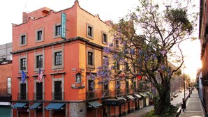 A hotel with a red facade, multiple windows, and a balcony. - Hotel Templo Mayor (Mexico City)