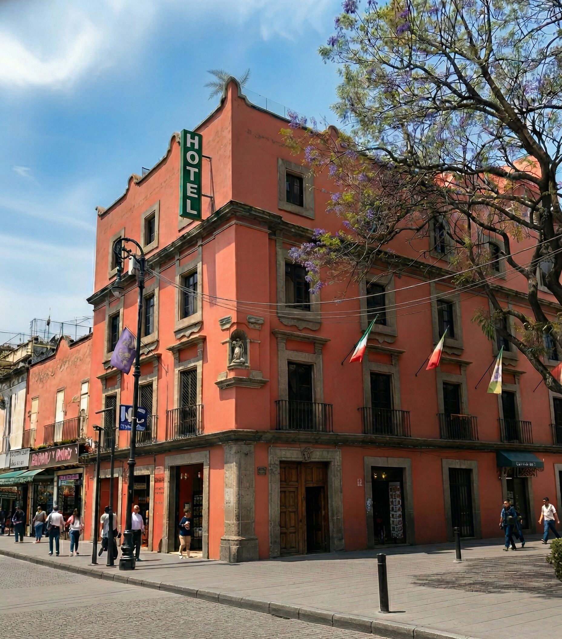 A hotel with a prominent sign, multiple balconies, and a cobblestone street.