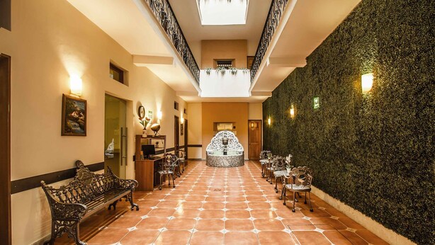A hotel lobby with a central fountain, benches, and a high ceiling with a skylight. - Hotel Templo Mayor (Mexico City)
