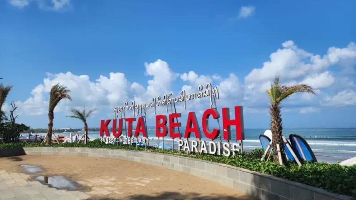 Un panneau indiquant la plage de Kuta avec l’inscription : « KUTA BEACH SUNSET IN THE LAST PARADISE ».