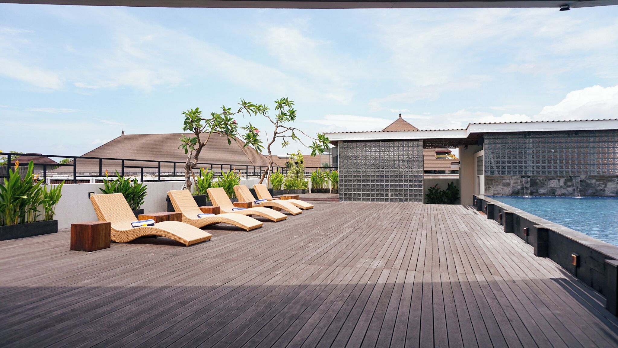 A wooden deck with lounge chairs and a pool.