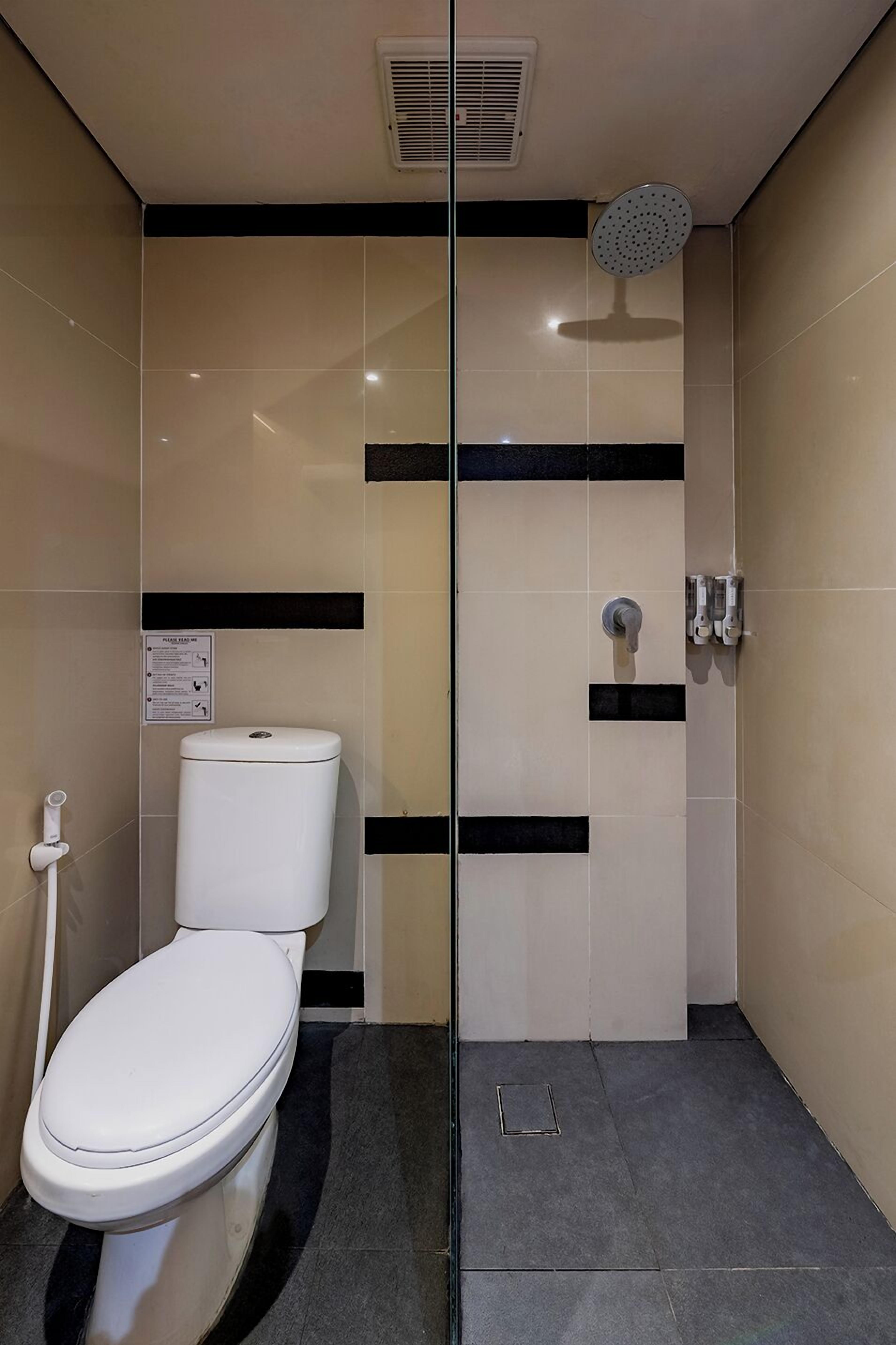 A modern bathroom with a toilet, a shower, and a hand dryer.