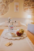 Une table soigneusement dressée, avec deux bouteilles de vin de Cetina, un bol de noix et deux pommes posées sur un chemin de table en dentelle.