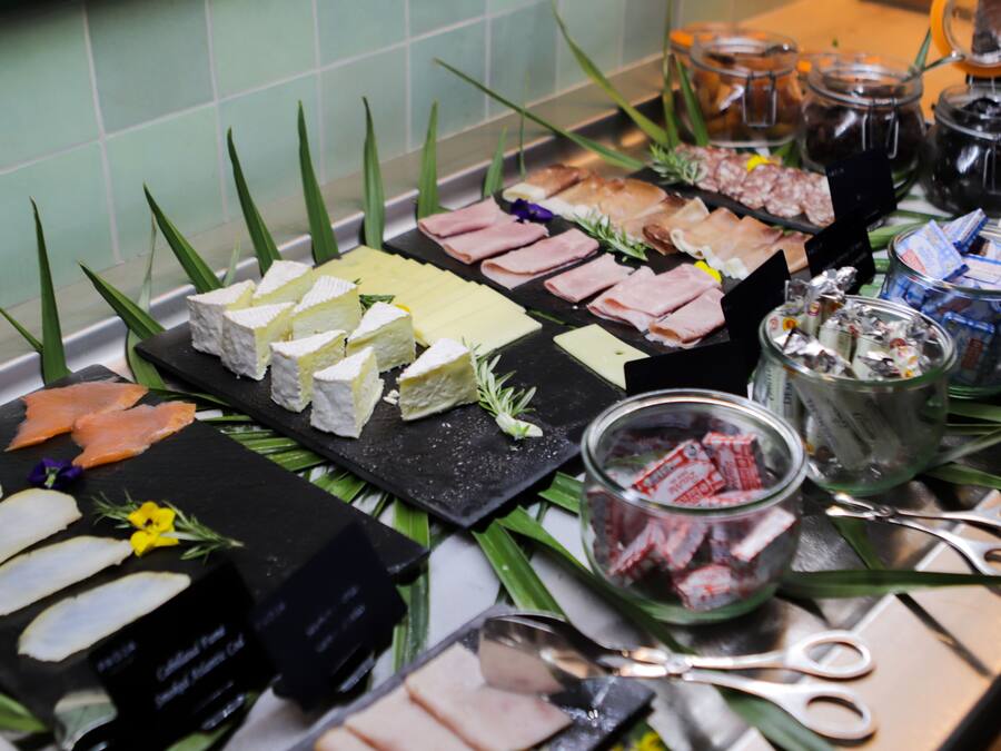 Un bufé con diversos alimentos, incluyendo queso, carnes y salsas.