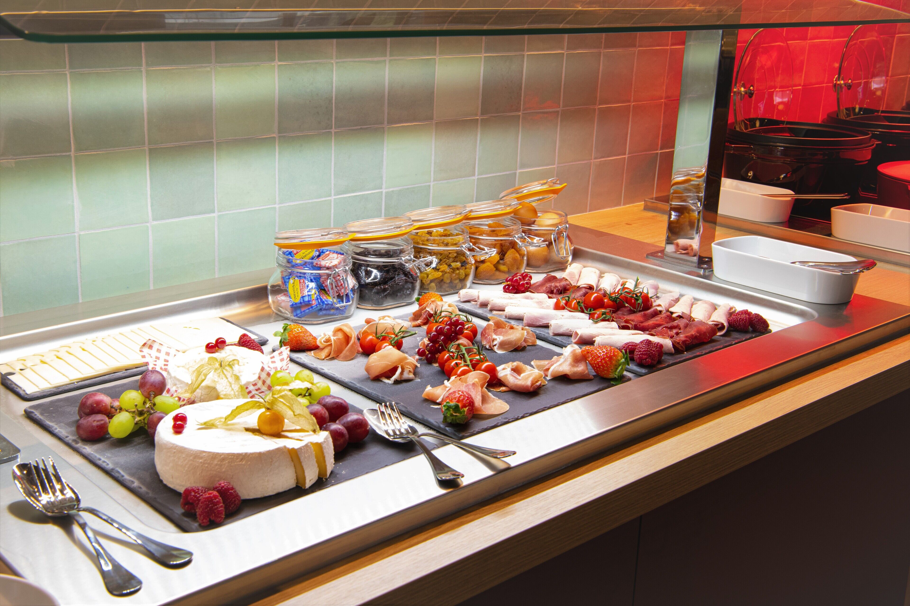 A buffet with various food items including fruits, cheeses, and meats.