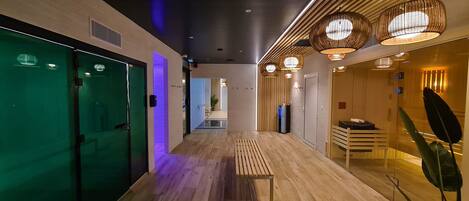 A modern hotel corridor with wooden flooring, glass doors, and ambient lighting.