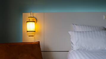 A hotel room with a bed, a small round table, and a wall-mounted lamp.