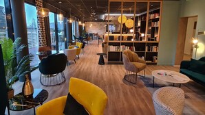 A modern lounge area with seating, a bookshelf, and a bar. - Padja Hotel & Spa, Vannes (Vannes)
