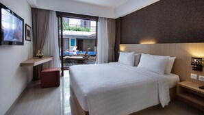 A hotel room with a large bed, a desk, a TV, and a balcony with a pool. - Sense Sunset Hotel Seminyak (Seminyak)