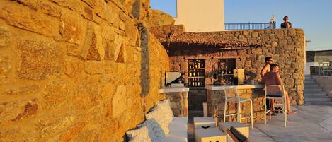A stone wall with a bar area, seating, and a staircase.