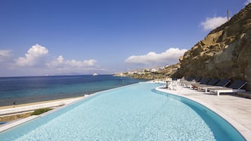 Una piscina al aire libre, sombrillas, sillones reclinables de piscina