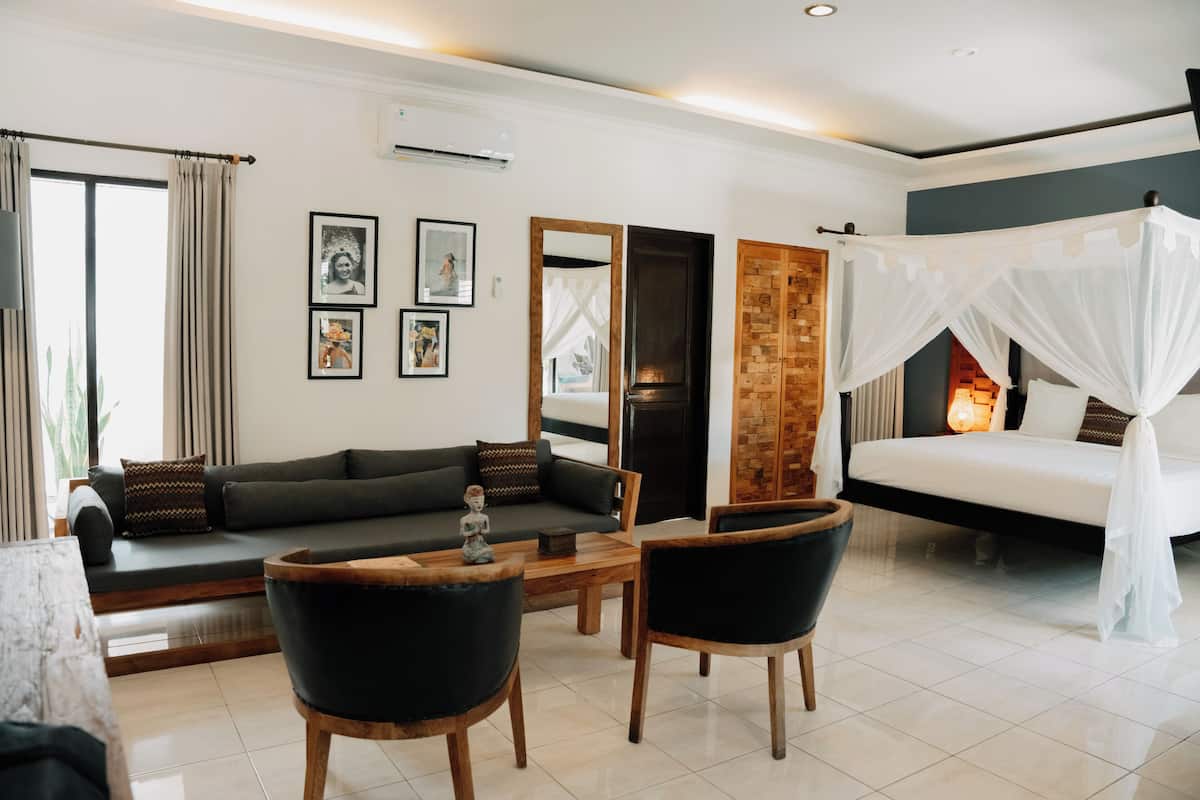 A modern living room with a sofa, chairs, a coffee table, and a bed with a canopy.