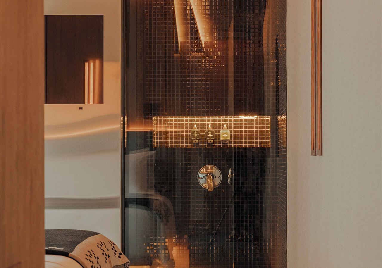 A bathroom with a tiled wall, a mirror, and a towel rack.