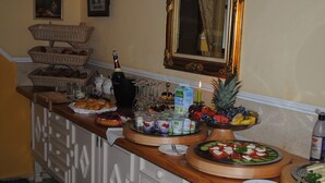 Montaje de buffet con diferentes opciones de comida, una botella de champán y un espejo sobre el mostrador.