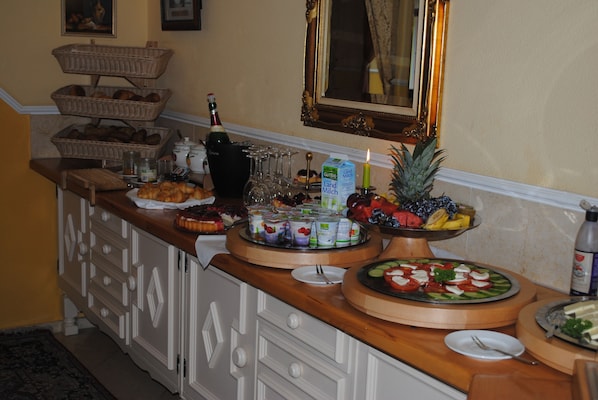 Montaje de buffet con diferentes opciones de comida, una botella de champán y un espejo sobre el mostrador.
