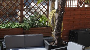 Un espacio al aire libre con sillones, una mesa y plantas, rodeado por una valla de madera.