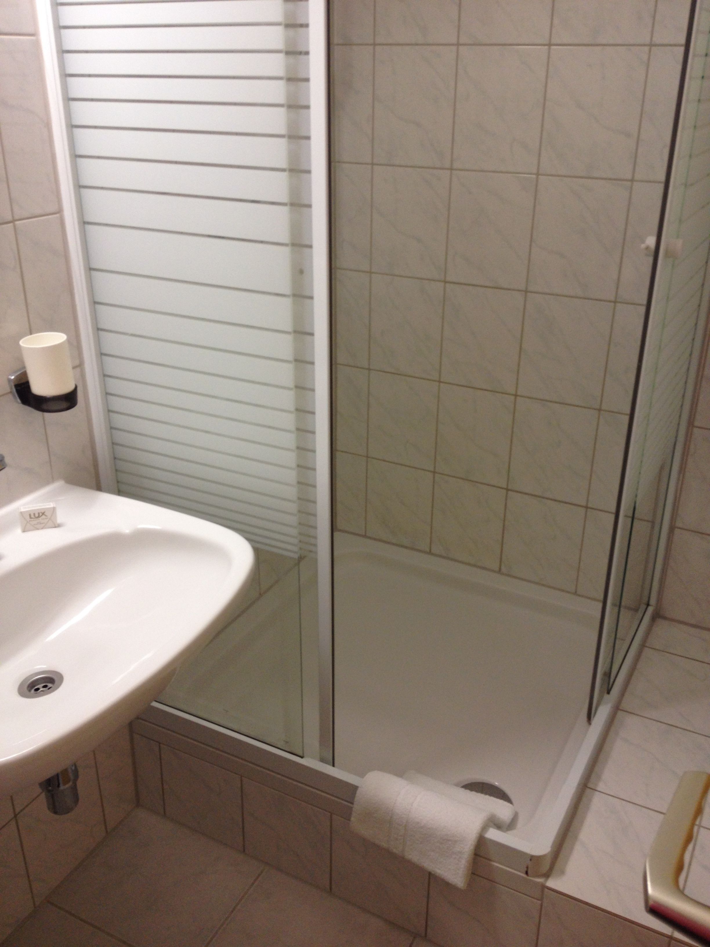 A bathroom with a white sink, a glass shower enclosure, and a towel hanging on the shower door.
