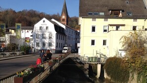 Un puente sobre un canal flanqueado por edificios, incluyendo un hotel llamado 'Hotel Elsenztal'.