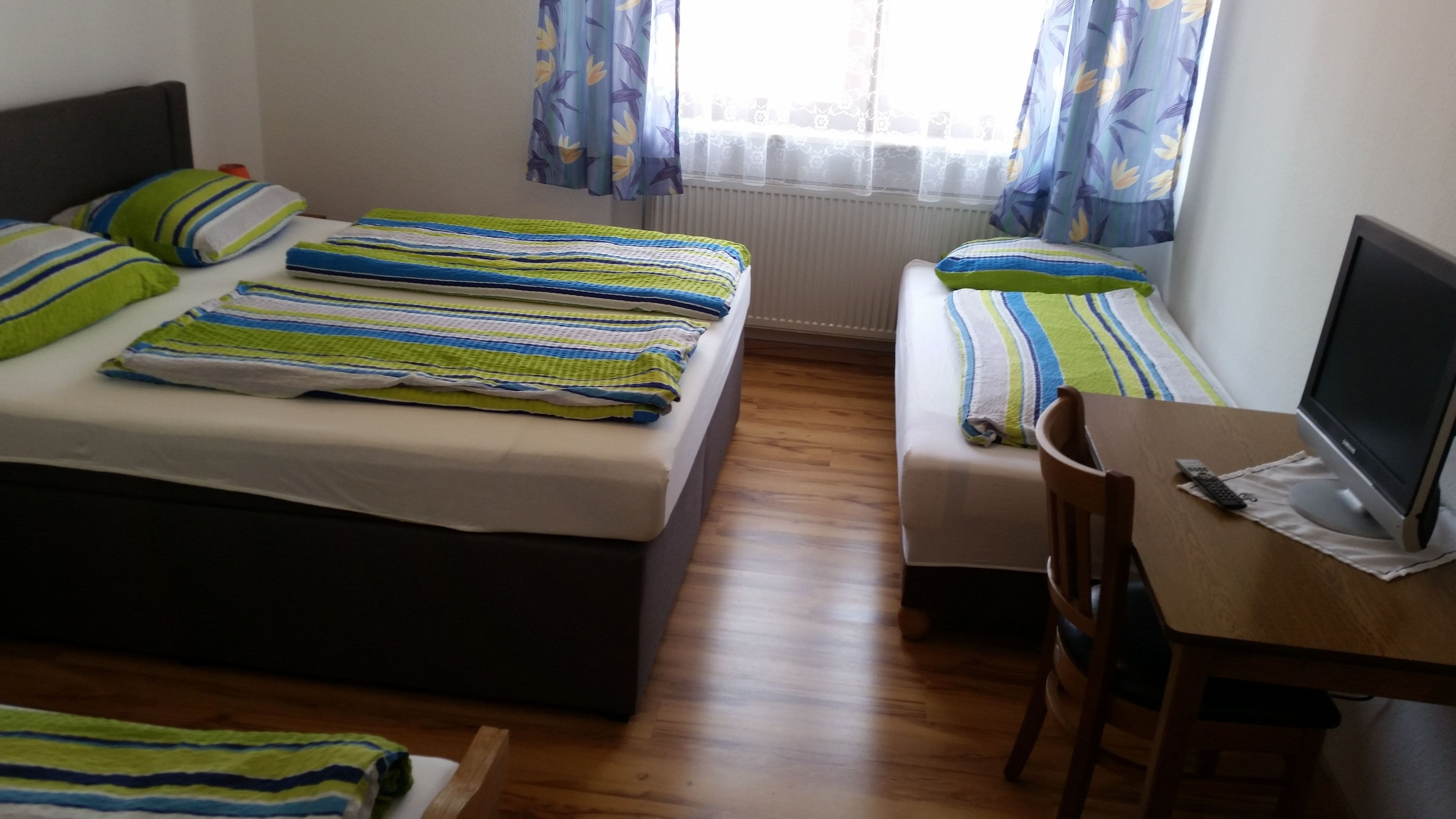 Une chambre avec deux lits, un bureau avec un ordinateur et une chaise.