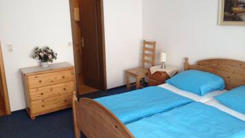 A bedroom with a wooden bed, a wooden dresser, a chair, a nightstand, and a painting on the wall.