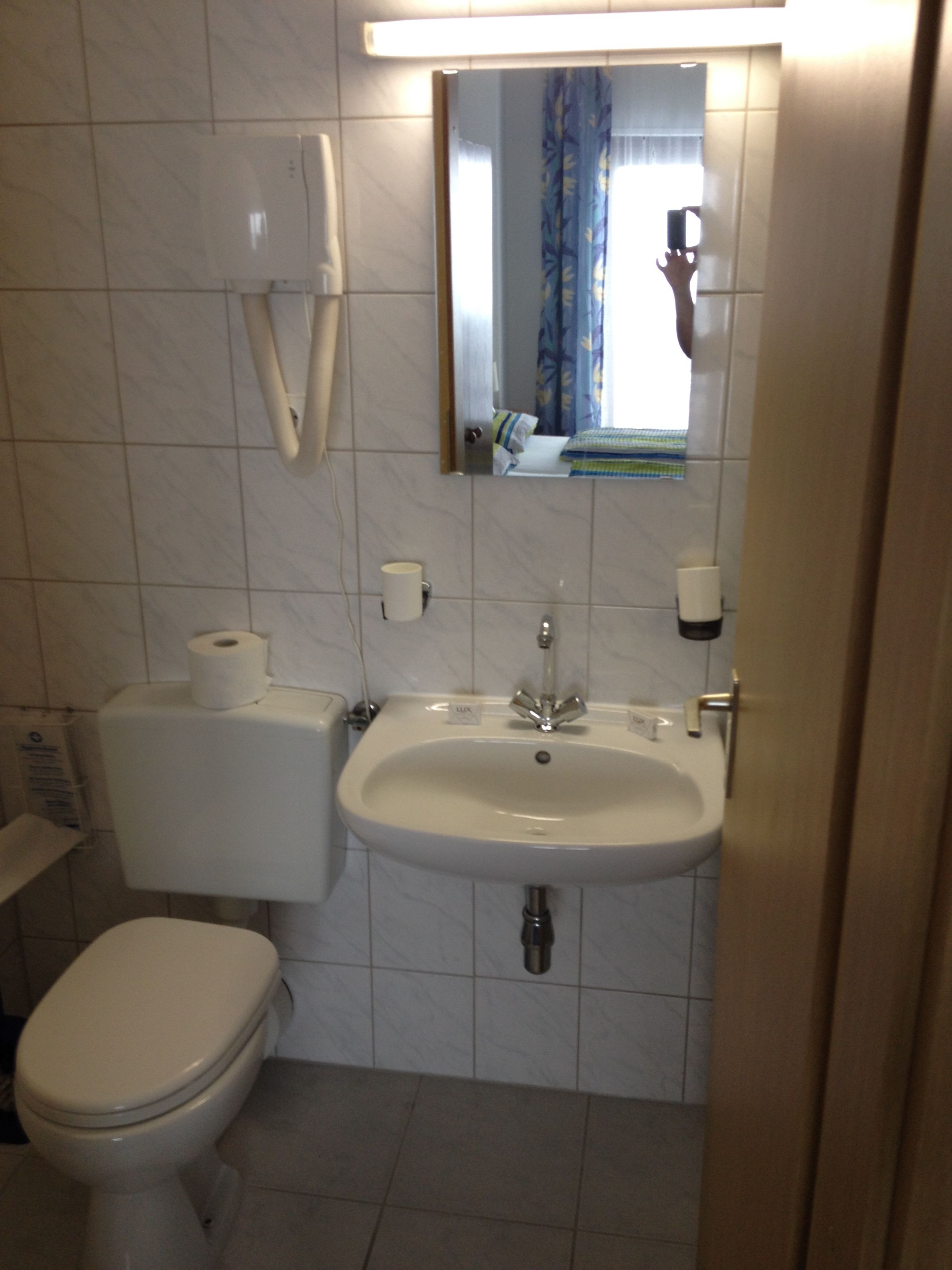 Un baño con inodoro, lavamanos y espejo.