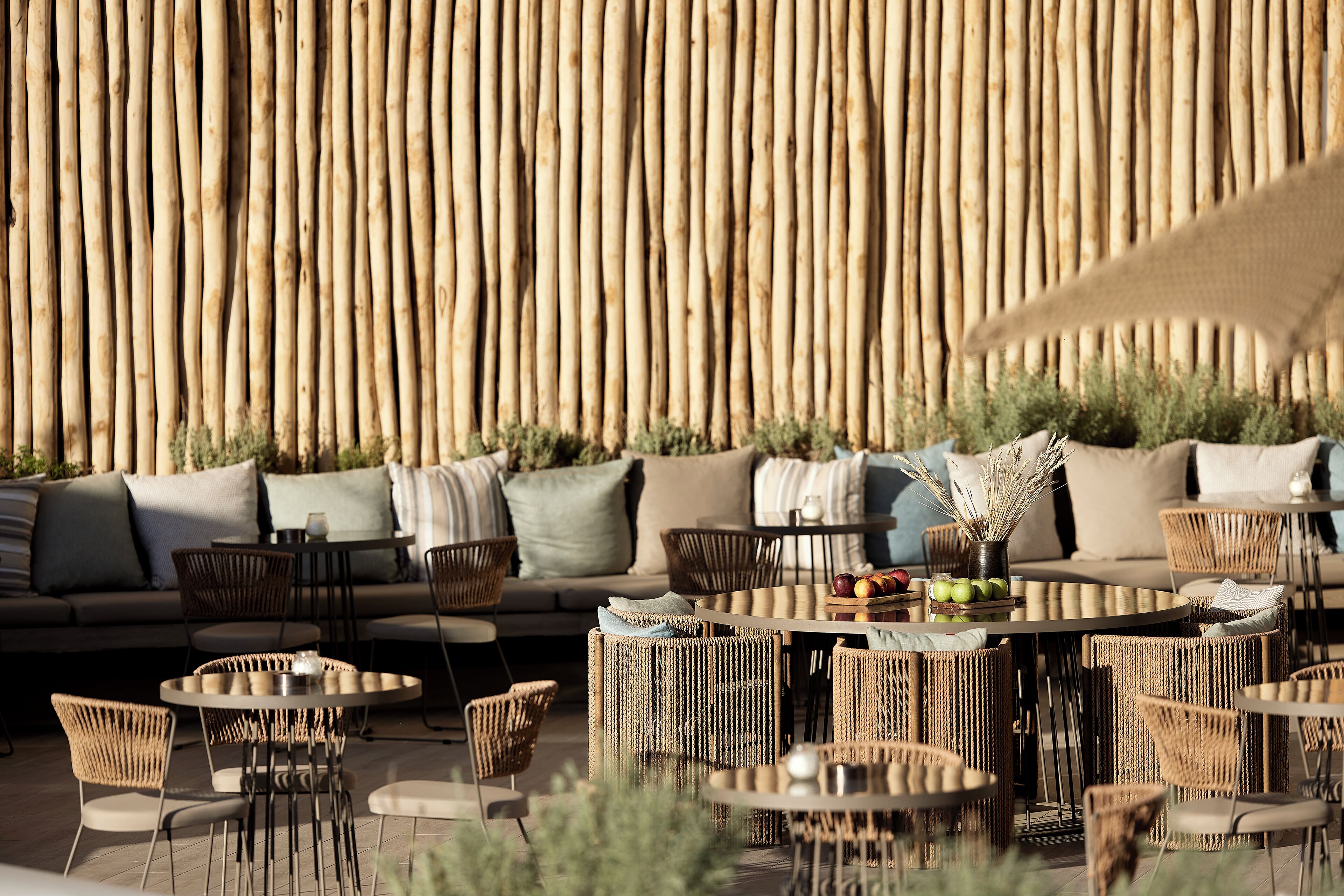 An outdoor seating area with wicker furniture, a round table, and a sofa with cushions.