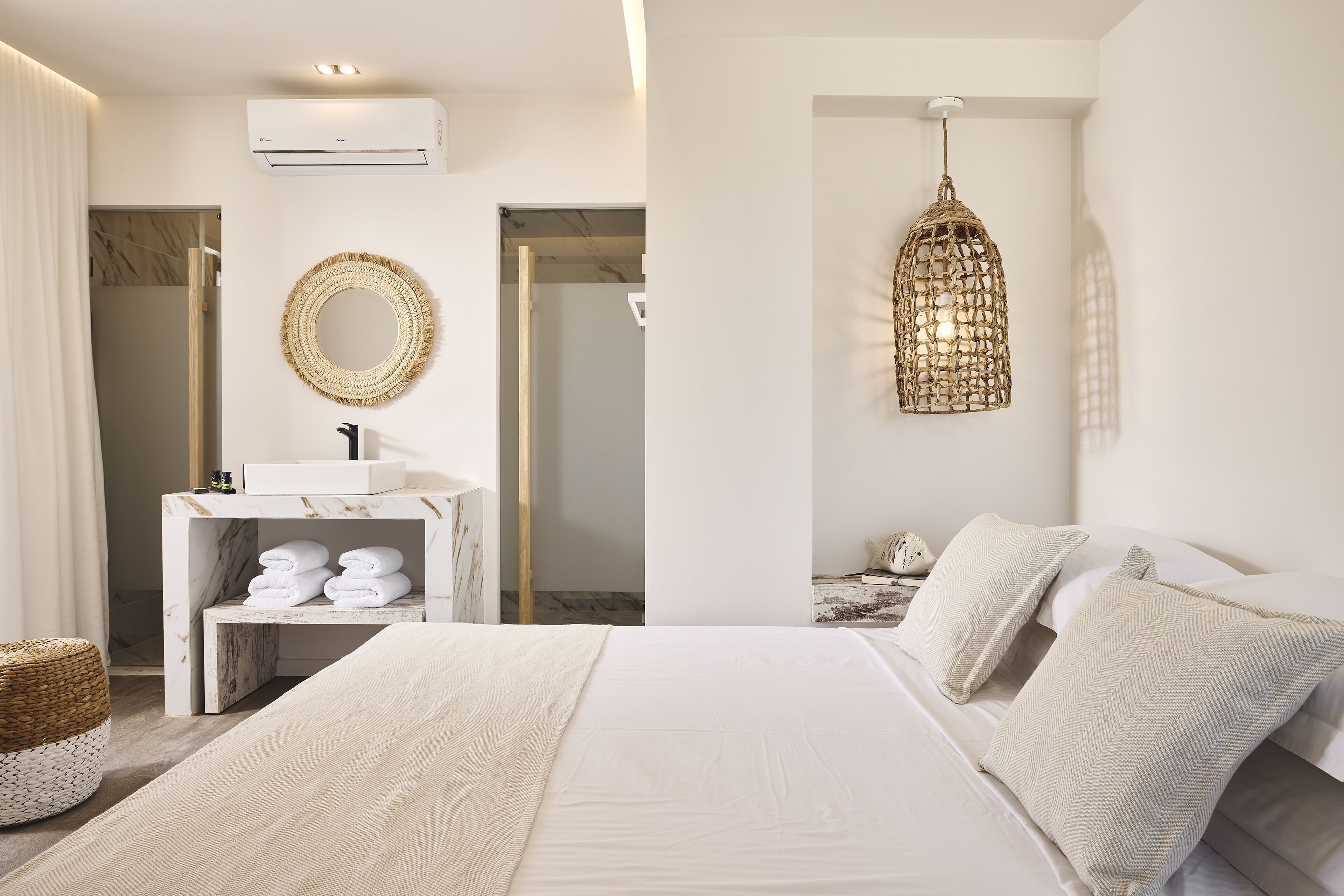 Ein modernes Schlafzimmer mit einem großen Bett, einem мраморном Nachttisch mit Handtüchern, einer Hängeleuchte und einem Badezimmer mit Dusche und Toilette.