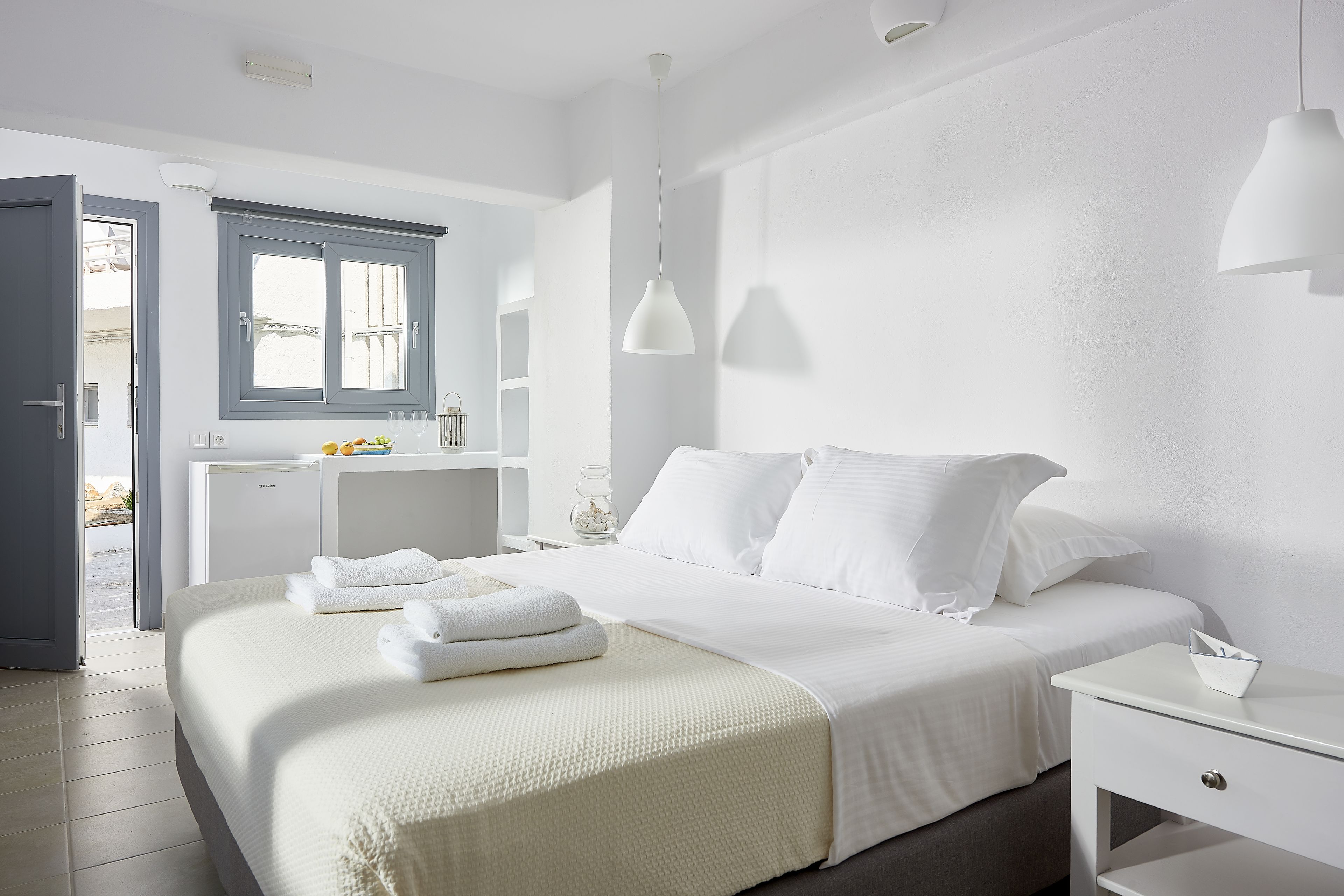 A hotel room with a bed, bedside table, and a window with a view.