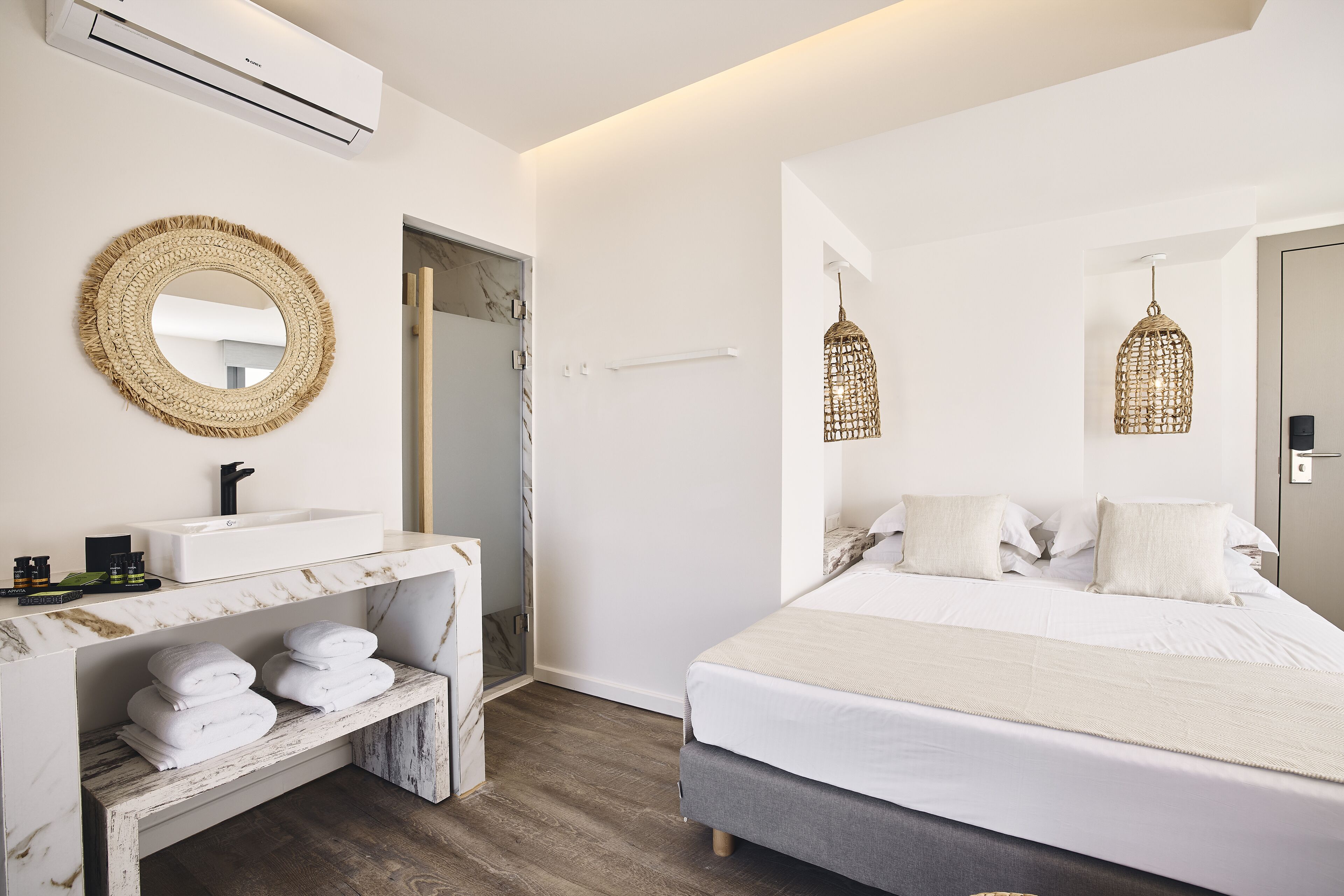 Un dormitorio moderno con cama, mesitas de noche, un espejo y una lámpara colgante.