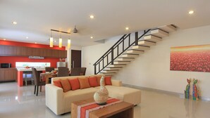 A modern living room with a sofa, coffee table, and a staircase. - Destiny Villas and Residence Seminyak (Keroboken Kelod)