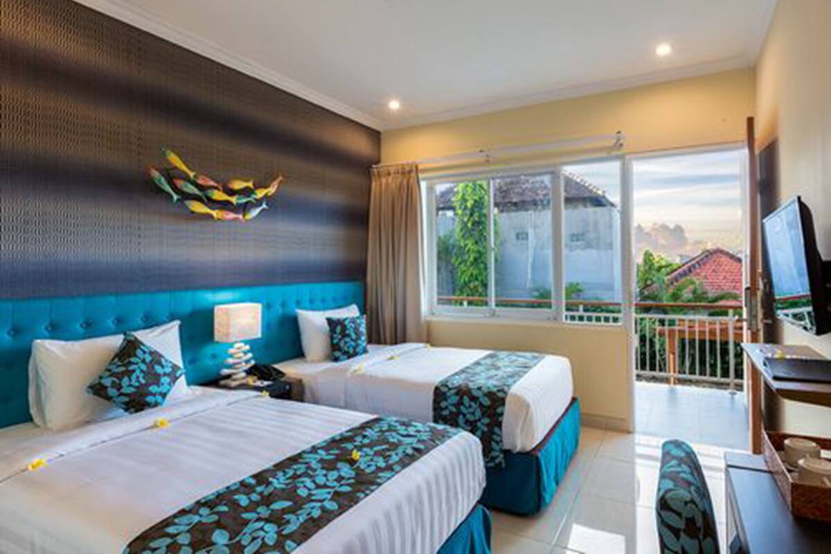 A hotel room with two beds, a balcony with a view, and a television.