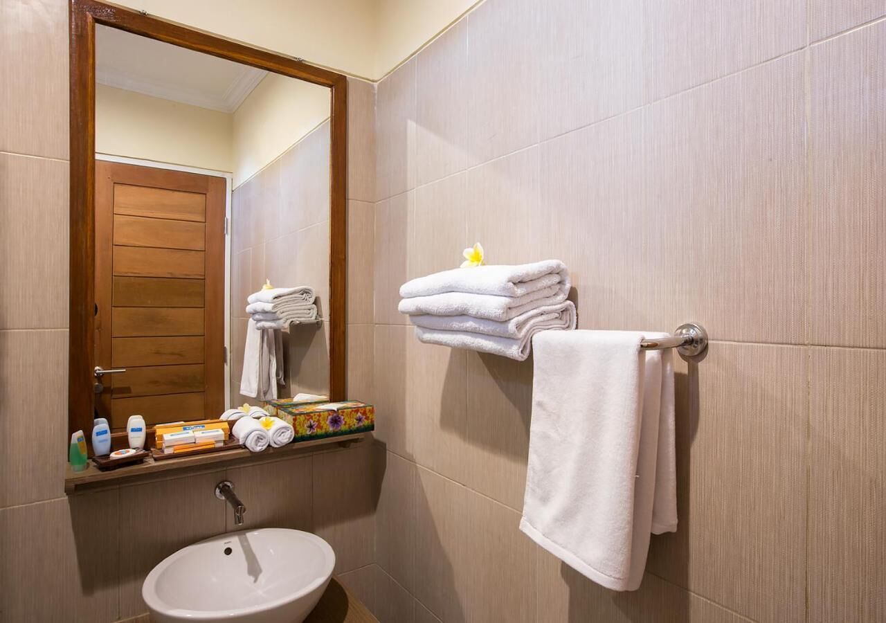 Un baño con lavabo, espejo, toallero y artículos de aseo.