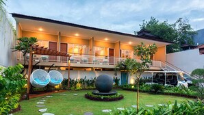 A hotel with a two-story structure, a covered outdoor seating area, and a well-maintained garden with a spherical sculpture and stepping stones. - Destiny Villas and Residence Seminyak (Keroboken Kelod)