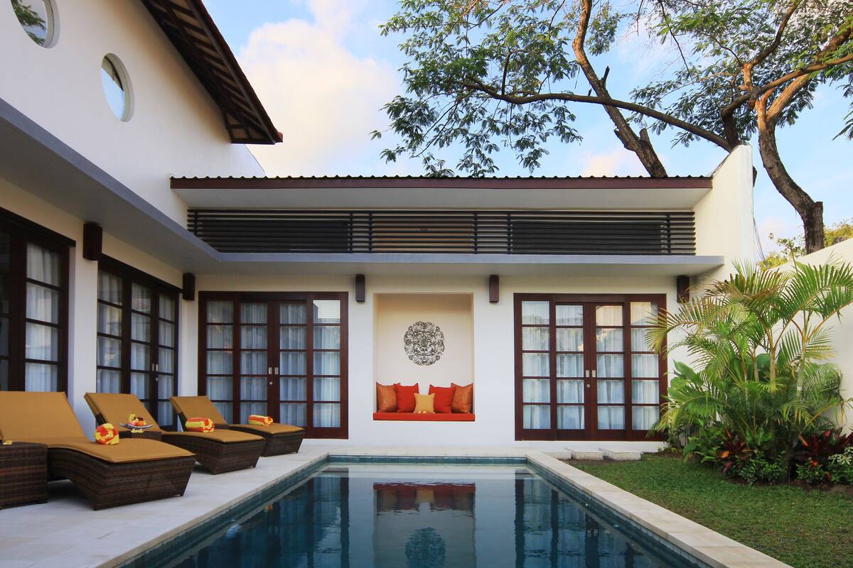 A poolside area with lounge chairs and a decorative wall.