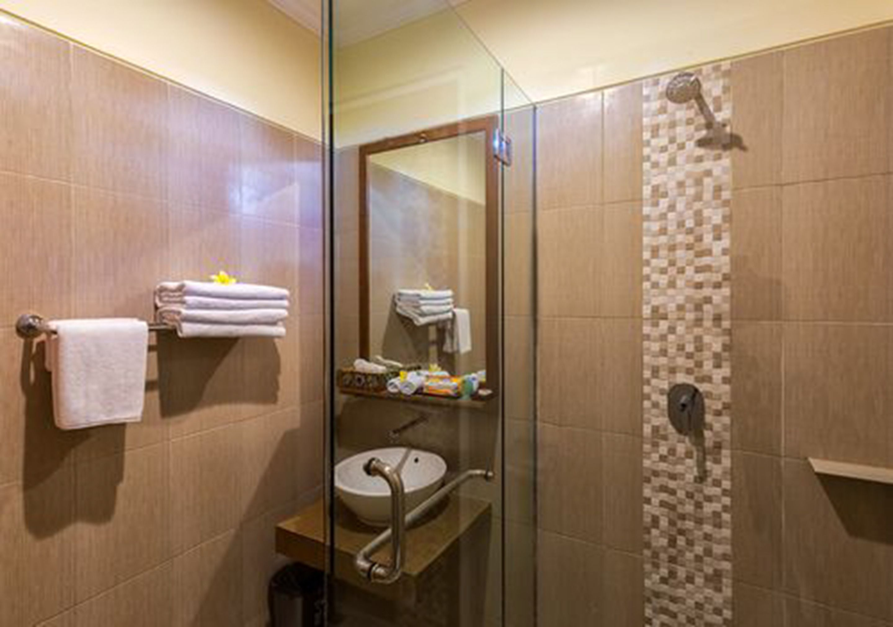 A modern bathroom with a glass-enclosed shower, a sink with a vanity, and neatly stacked towels on a rack.
