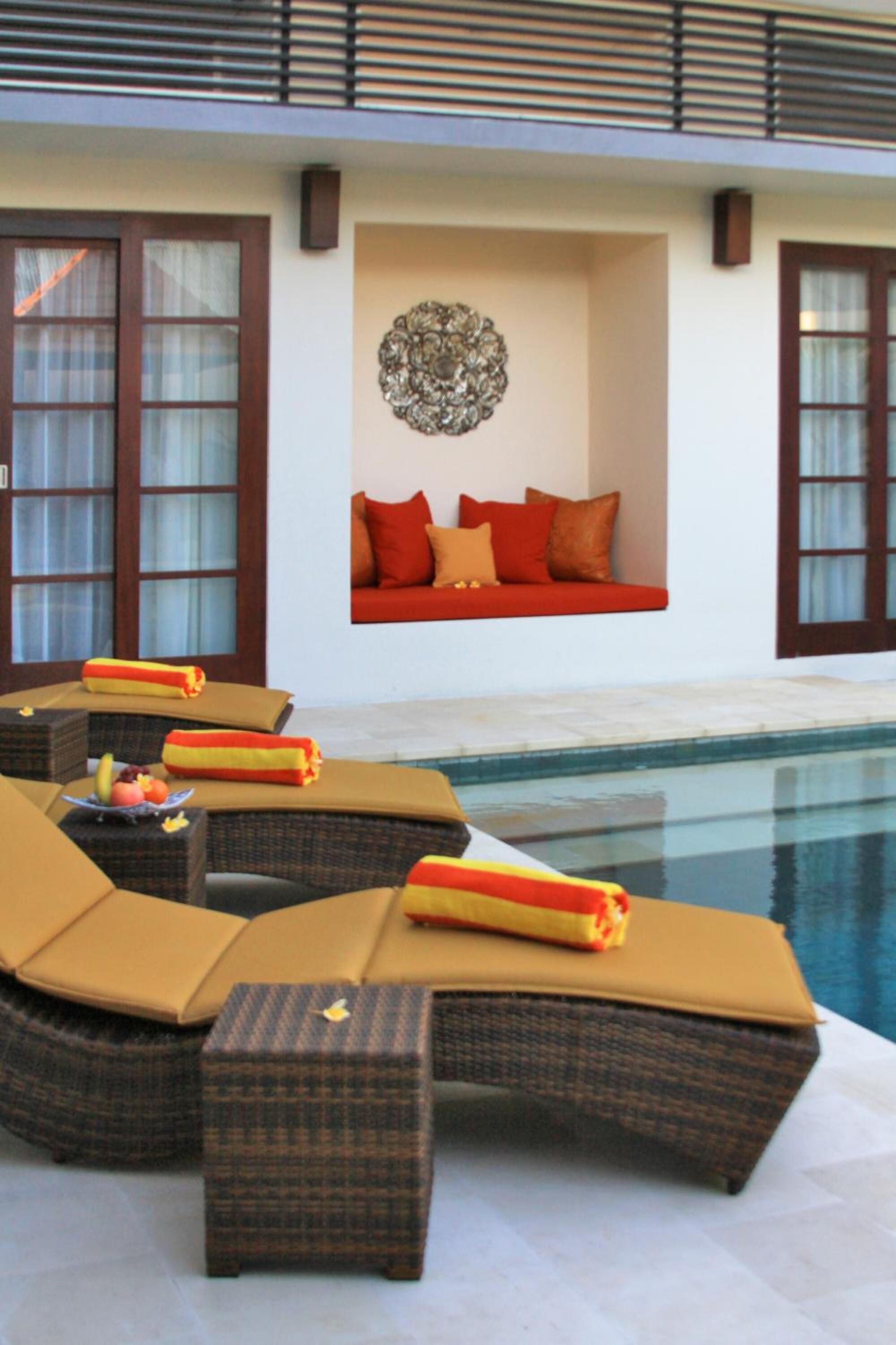 Ein Poolbereich mit Liegestühlen und einer Sitzecke, einem Wandkunstwerk sowie Blick auf den Pool.