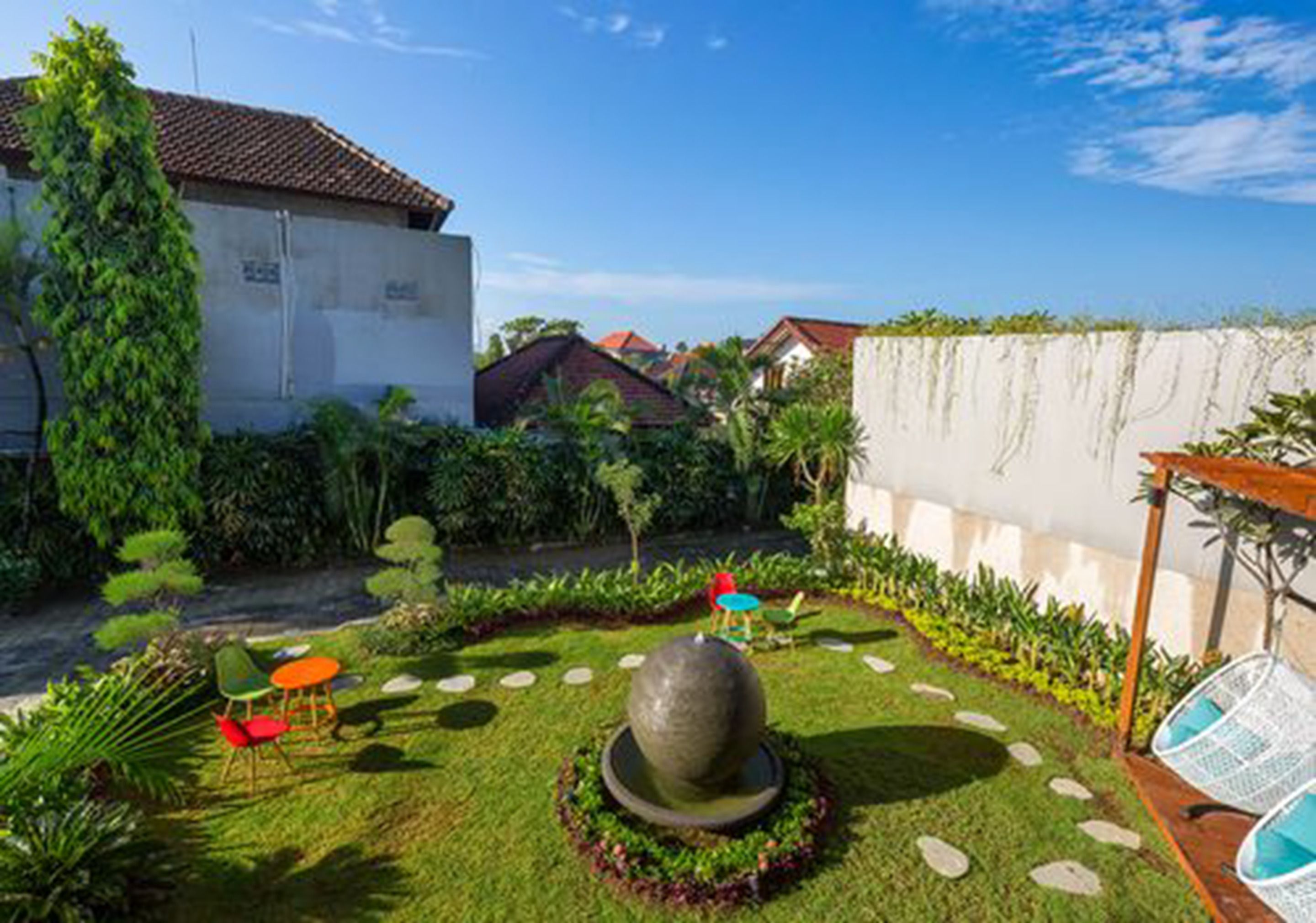A courtyard with a central water feature, surrounded by greenery and a few outdoor seating areas.