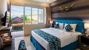 A hotel room with a large bed, a desk, and a view of the outside. - Destiny Villas and Residence Seminyak (Keroboken Kelod)