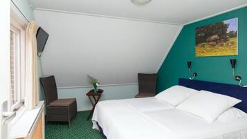 Een slaapkamer met een bed, twee stoelen, een tafeltje met een plant, een schilderij aan de muur en een raam met gordijnen.