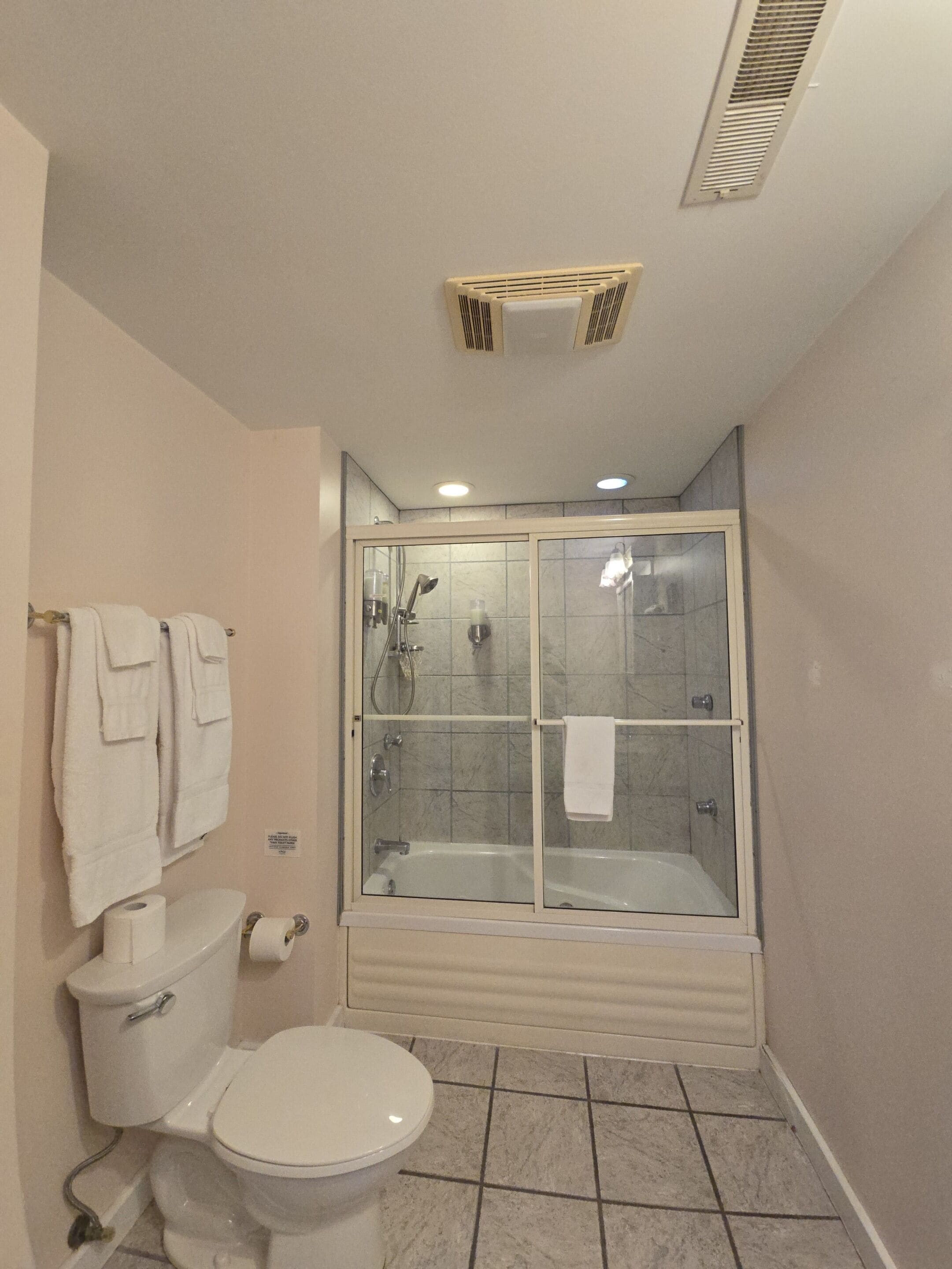 Une salle de bain comprenant des toilettes, une douche à parois de verre et une baignoire.
