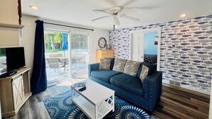 A living room with a blue sofa, a white coffee table, and a ceiling fan. - New Buffalo Inn (New Buffalo)
