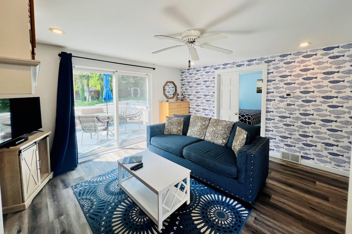 Un salon avec un canapé bleu, une table basse blanche et un ventilateur de plafond.