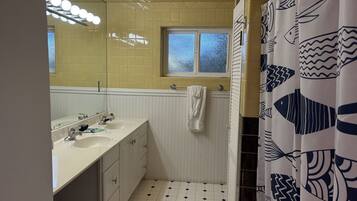 Un baño con dos lavamanos, una ventana y una cortina de ducha con motivos de peces.