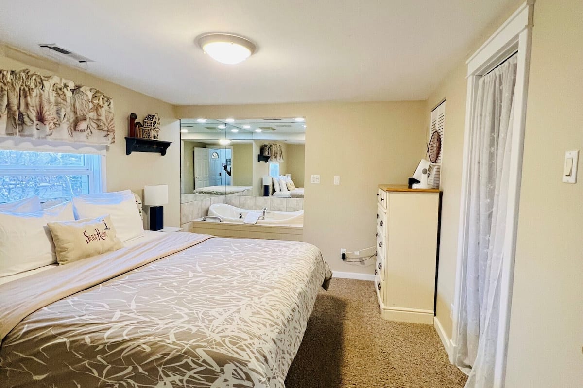 Une chambre avec un grand lit, un dressing et une salle de bain avec baignoire.