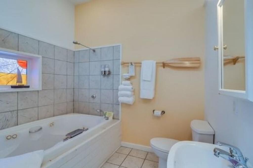 Un baño con bañera, inodoro, lavamanos y toallero.