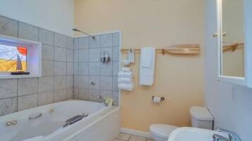 Un baño con bañera, inodoro, lavamanos y toallero.