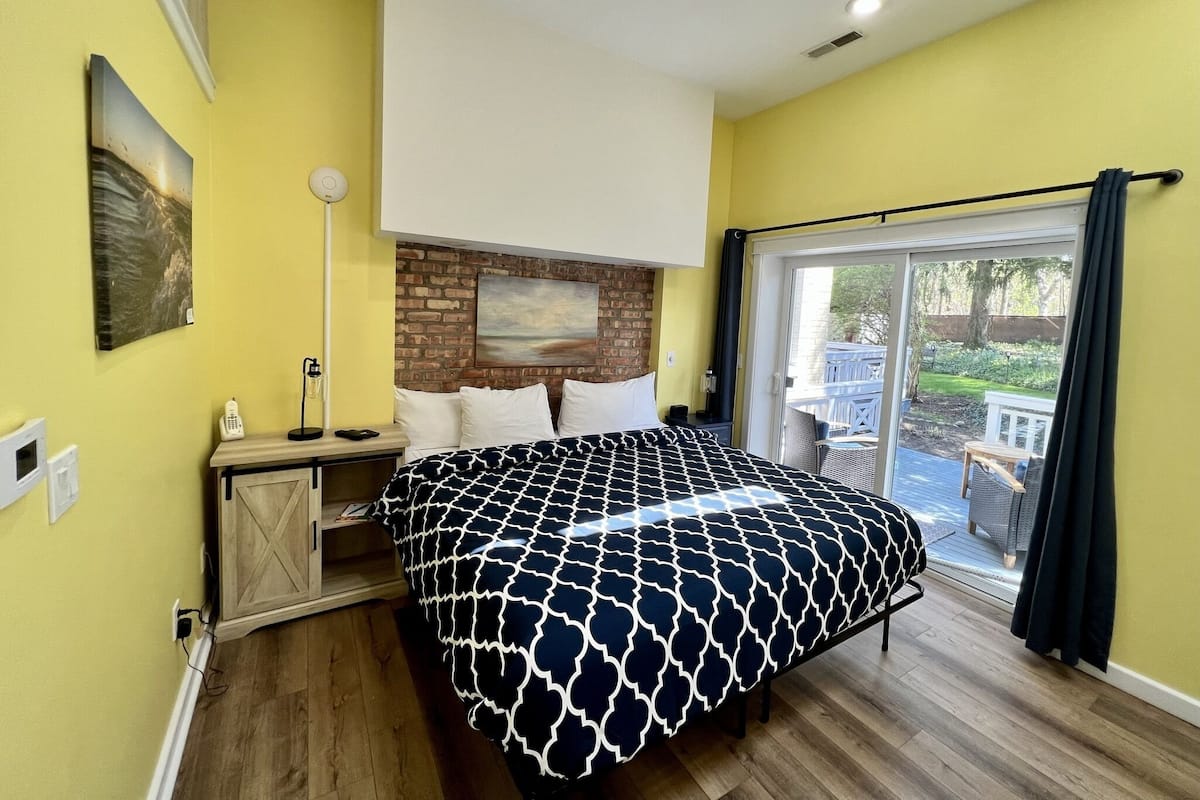 Une chambre à coucher avec un lit, une table de chevet, une lampe, un téléphone et un tableau accroché au mur.