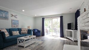 A living room with a blue sofa, white coffee table, and a fireplace. - New Buffalo Inn (New Buffalo)