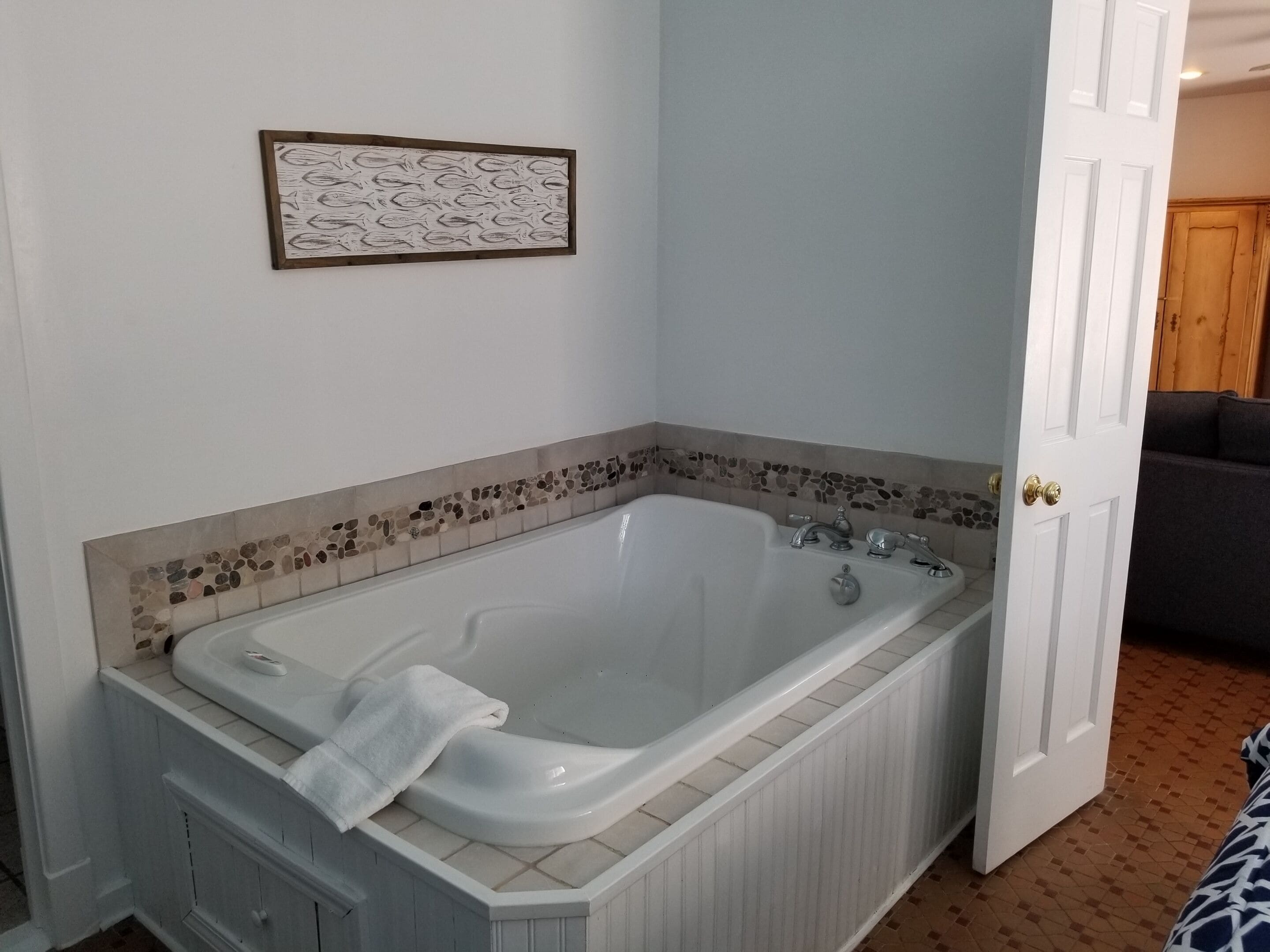 Une salle de bain avec une baignoire sur pieds, une serviette posée sur le bord de la baignoire et une bordure décorative en mosaïque.
